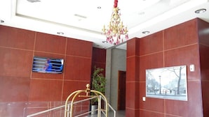 A hotel lobby with a staircase, a chandelier, a framed picture on the wall, and a television screen. - Palette Top Stars Hotel (Abu Dhabi)