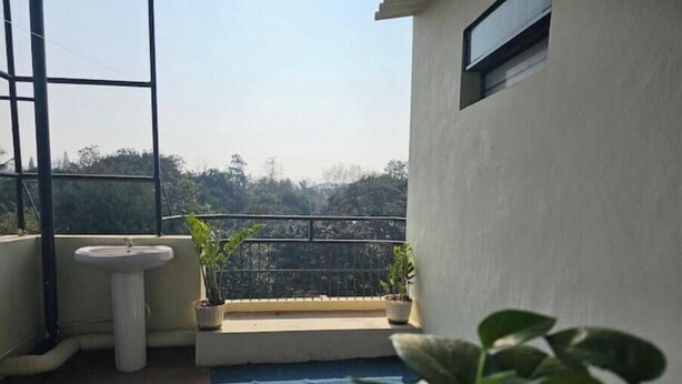 A balcony with a sink, potted plants, and a view of a hilly landscape. - Blumint 303 (Bengaluru)