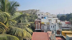 A multi-story residential building with a red-tiled roof, surrounded by greenery and palm trees. - Blumint 303 (Bengaluru)