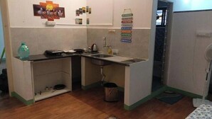 A compact kitchen with a sink, countertop, and a small trash bin.