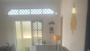 A bedroom with a bed, a desk, and a chair. There is a window with a view of the outside.