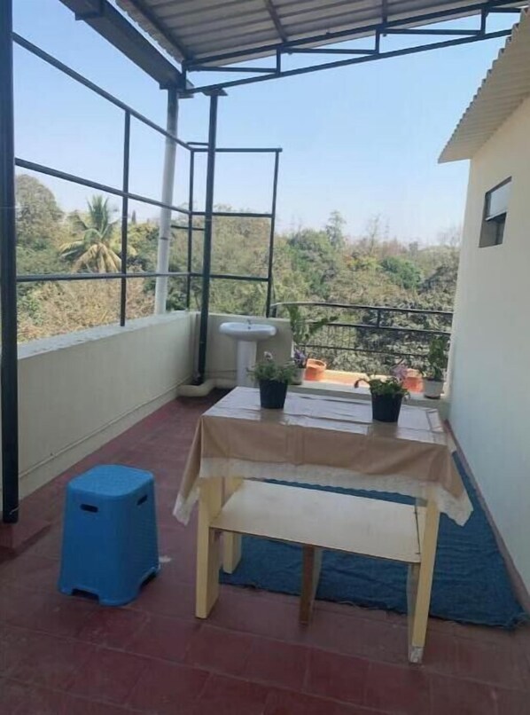 Petit balcó amb una taula, un tamboret i plantes en testos.
