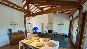 A dining area with a table set for four, a sofa, and a fireplace in the background.