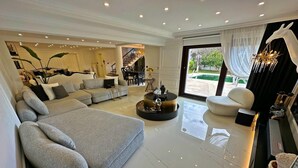 A spacious living room with a grey sofa, a round coffee table, and a dining area in the background. - Cloud Nine by Alara | Luxury Private Pool & Garden Villa (İstanbul)