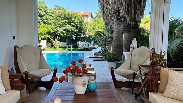 A sunlit room with a pool view, featuring two beige sofas, a wooden coffee table, and decorative vases. - Cloud Nine by Alara | Luxury Private Pool & Garden Villa (İstanbul)
