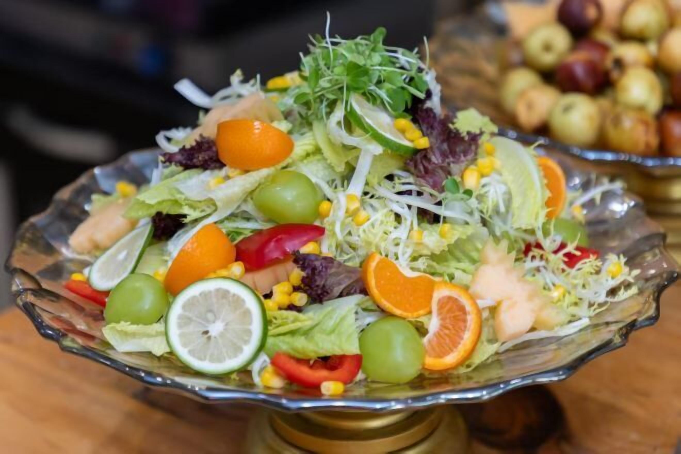 Ensalada en un bol de vidrio con diversas verduras y frutas.