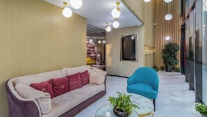 Eine moderne Lobby mit Sofa, Sessel und Couchtisch, ausgestattet mit Holzboden und Zimmerpflanzen.