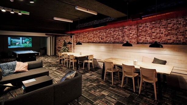 A conference room with a long table, chairs, a sofa, and a TV screen.