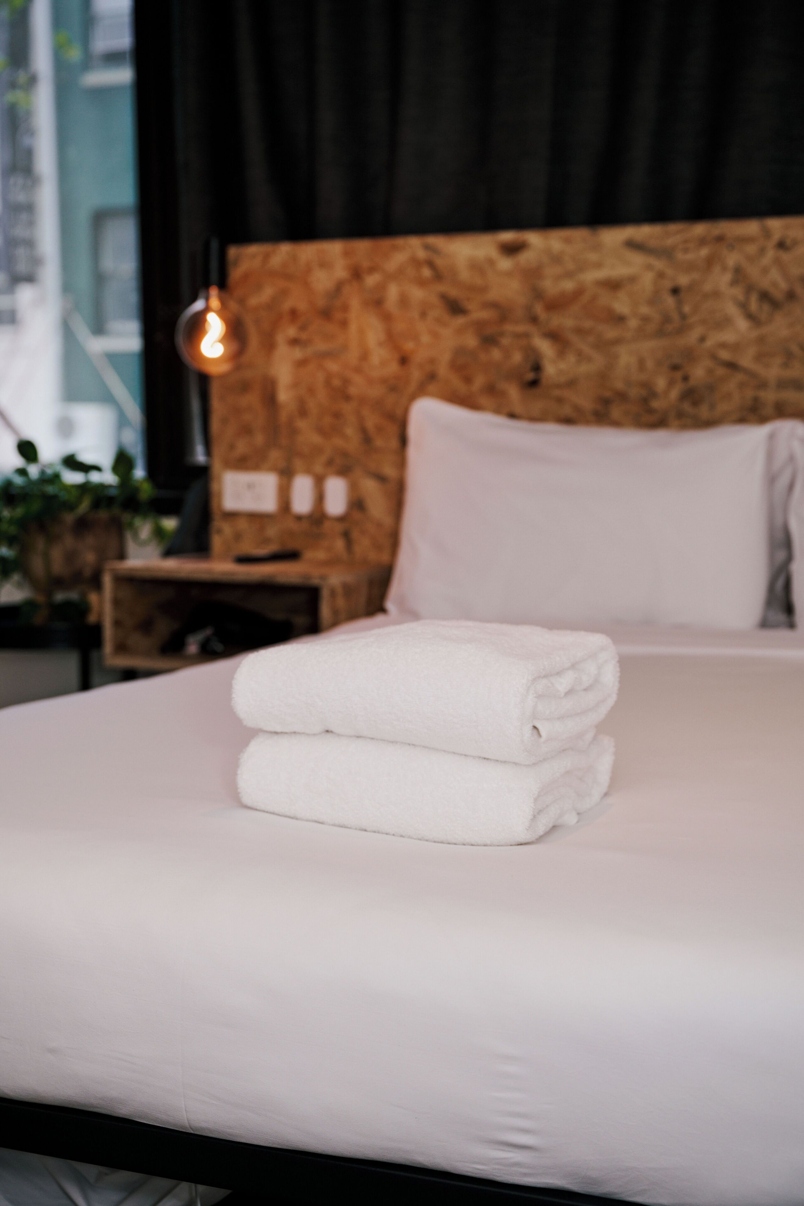 Una cama bien hecha con sábanas blancas y cabecero de madera.