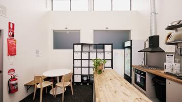 Una cocina moderna con una mesa de madera, sillas, horno empotrado y campana extractora negra.