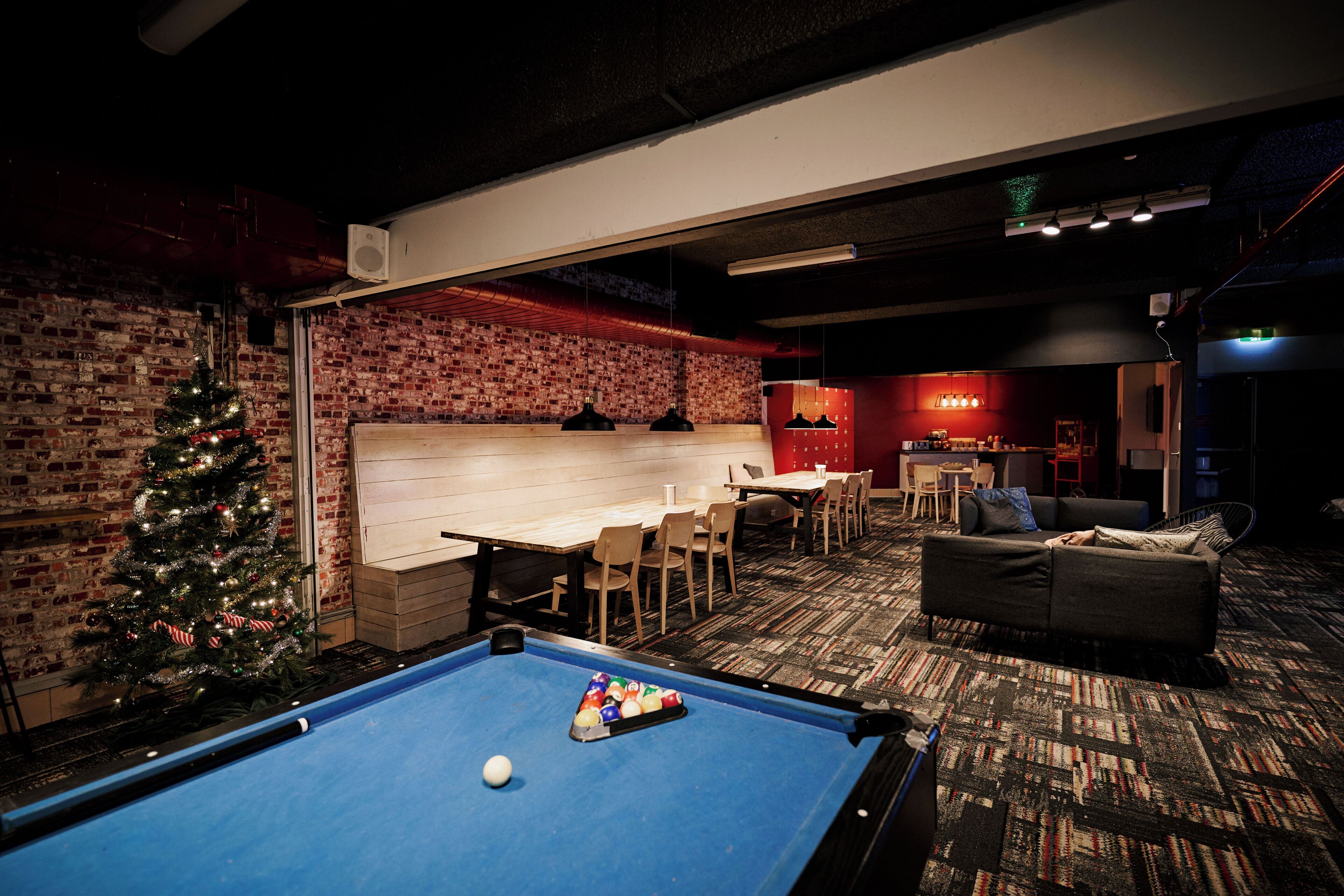 A pool table with balls, a Christmas tree, and a bar area with stools and a counter.