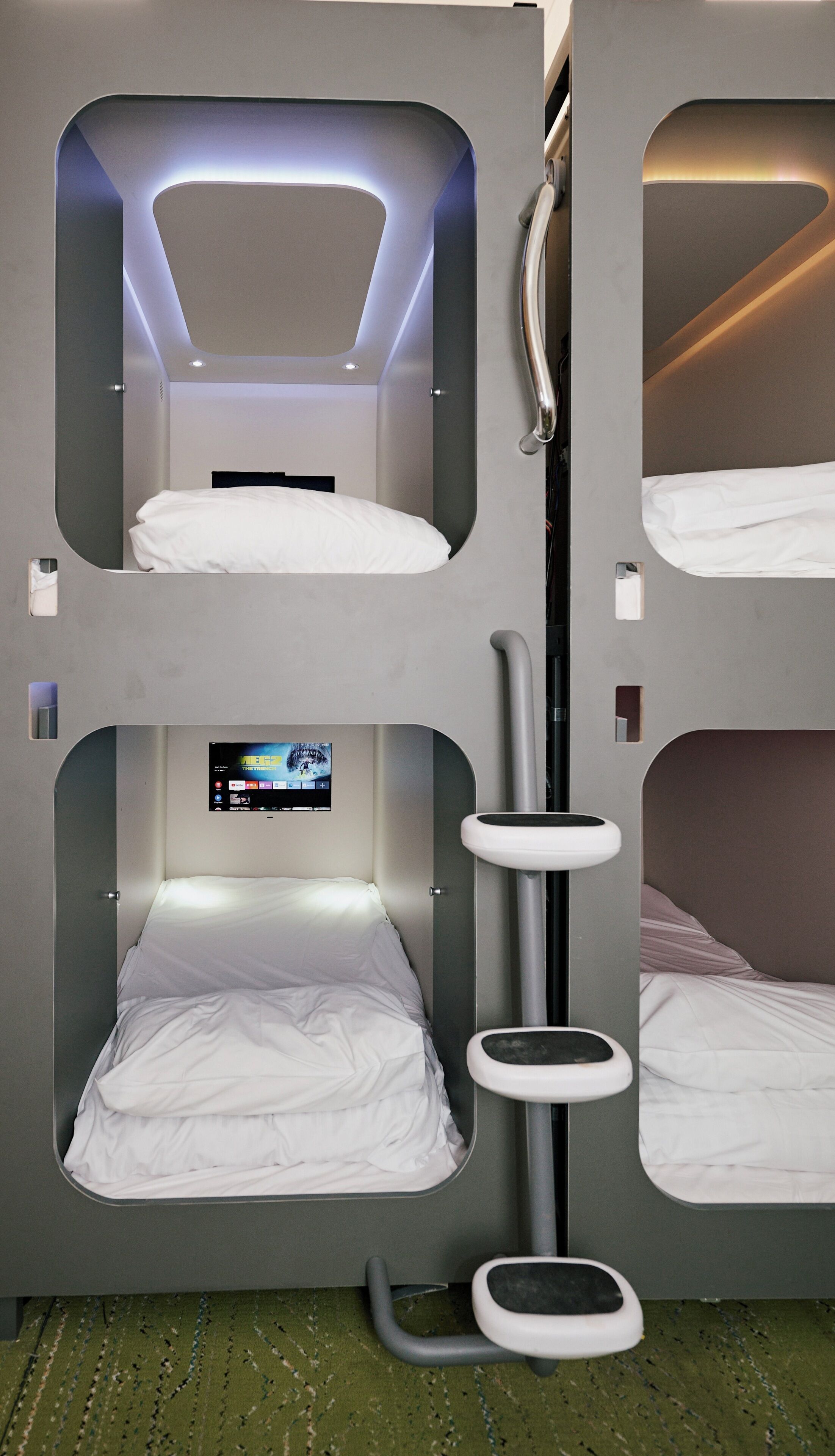 Camera con letto a castello, schermo televisivo, un piccolo tavolo e una lampada a parete.