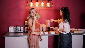 A kitchen counter with toasters, a refrigerator, and a hanging light fixture.