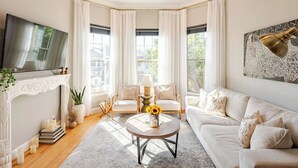 A living room with a fireplace, a sofa, a coffee table with flowers, and a TV.