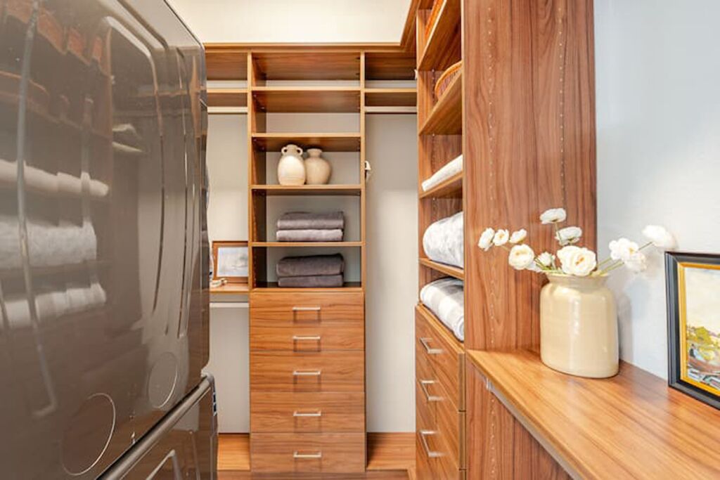 Un vestidor con estanterías de madera, cajones y un espejo.