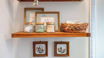A wooden shelf with jars, framed pictures, and a woven basket.