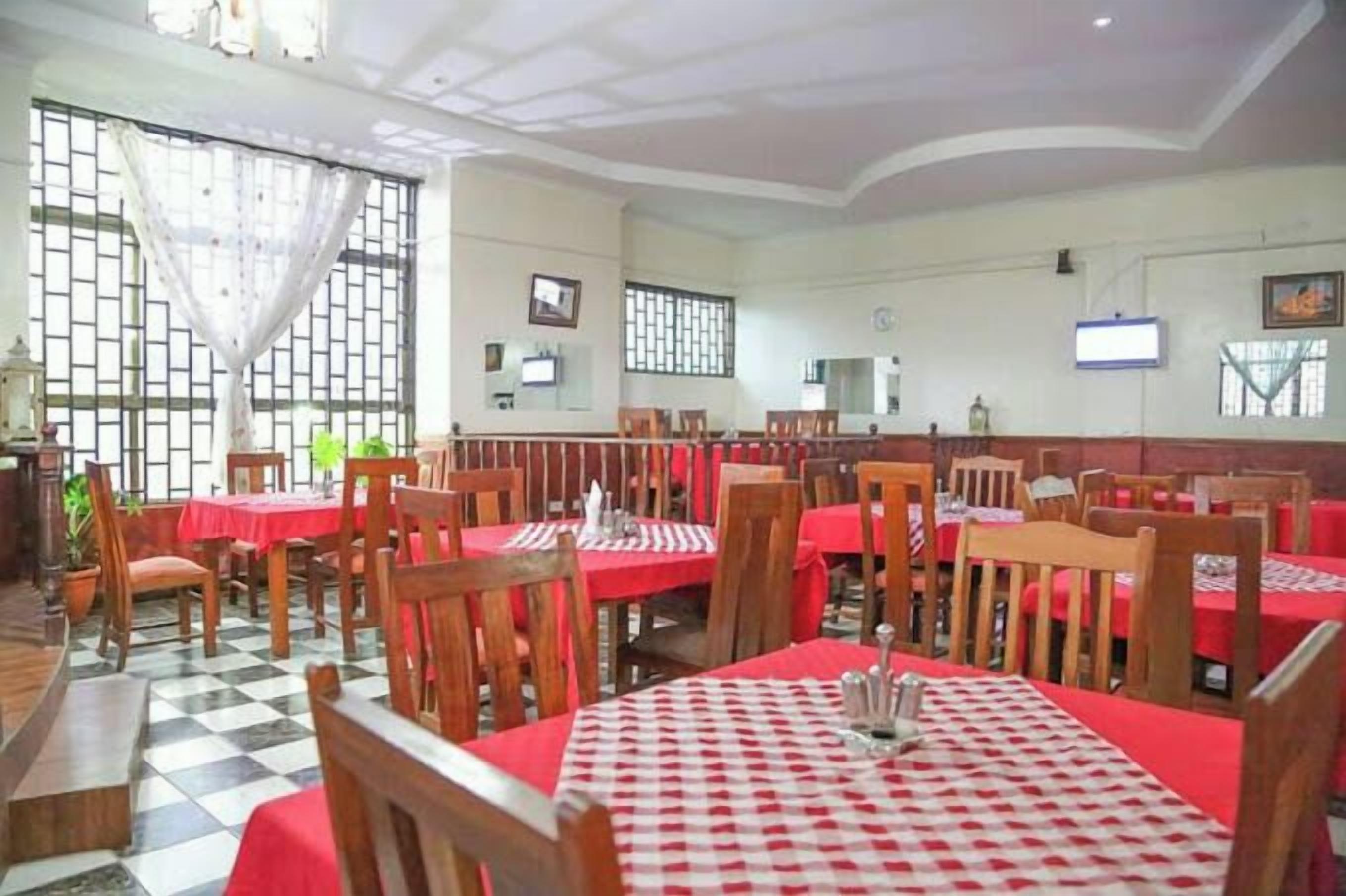 Un restaurante con pisos de baldosas a cuadros, manteles rojos y sillas de madera.