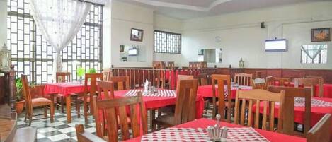 Un restaurante con pisos de baldosas a cuadros, manteles rojos y sillas de madera.