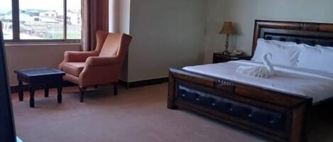 A hotel room with a bed, a chair, a small table, and a TV.