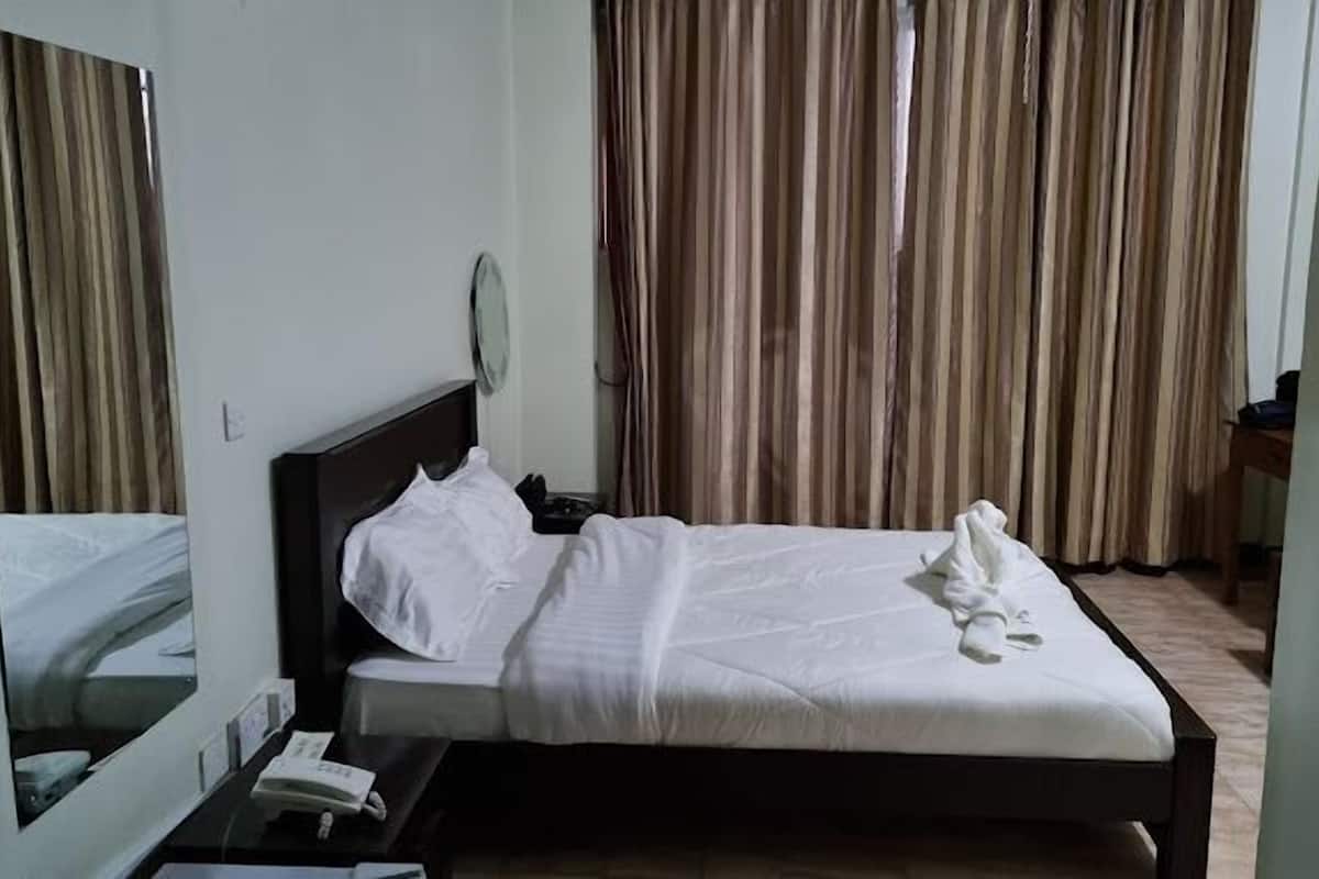 Una habitación de hotel con cama, mesita de noche y espejo.