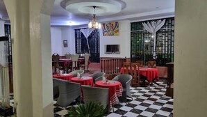 Un restaurant avec des tables rondes, des chaises en osier et un sol à carreaux.