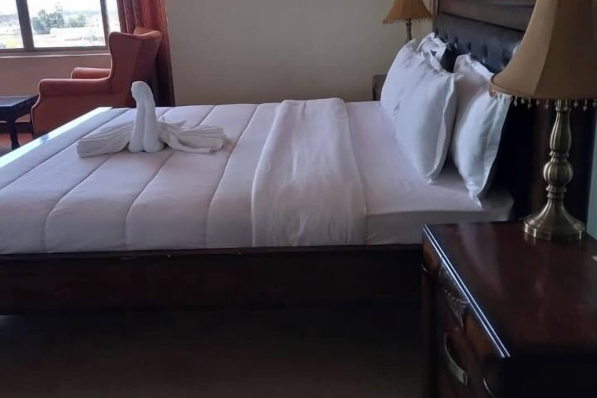 Una habitación de hotel con una cama grande, una mesita de noche de madera, un escritorio y una silla.