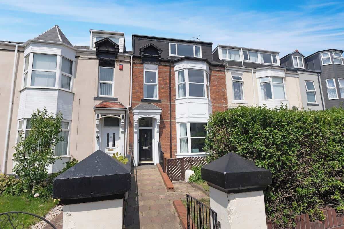 A row of terraced houses with a central entrance, a brick facade, and a small front garden.