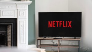 Una sala de estar moderna con chimenea, un televisor sobre un mueble de madera y una estantería.