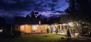 A two-story building with a brick facade, a covered porch, and a well-lit entrance. - Hosteria y Camping WiM (Machachi)