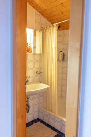 Ein Badezimmer mit einem weißen Waschbecken, einem Spiegel und einer Duschvorhang.
