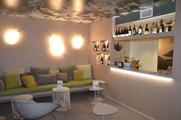 A modern lounge area with a sofa, chairs, and a bar with various bottles. - Seele Garda Hotel (Nago-Torbole)
