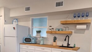 A modern kitchen with white cabinets, a wooden countertop, and a dining area with a round table and chairs. - Breezy Loft at Palmetto, FL. (Palmetto)
