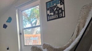 A room with a large window, a chair, and a wall sign that reads "HOME is where family is". - Breezy Loft at Palmetto, FL. (Palmetto)
