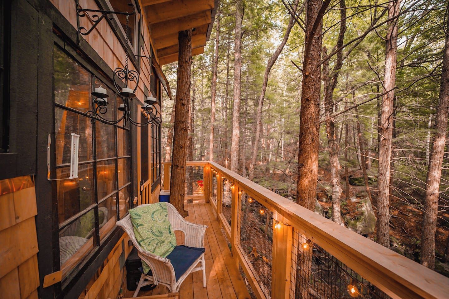 A wooden deck with a chair and a table, surrounded by a forest.