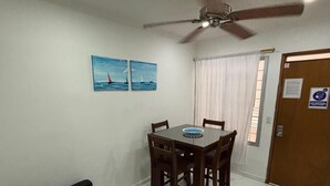 A dining area with a table and chairs, a ceiling fan, and a door with a sign. - A few steps from the beach in El Rodadero (Santa Marta)