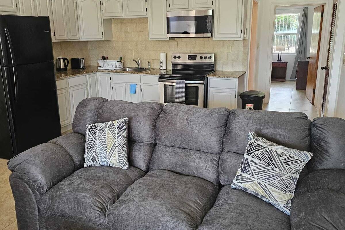 A compact kitchen with white cabinets, a black refrigerator, a microwave, a stove, and a sink.