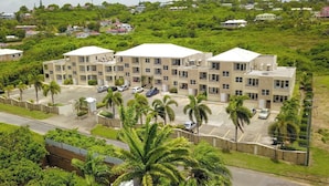 A multi-story hotel with a parking lot and palm trees in front. - Aurela Residences (St. John's)