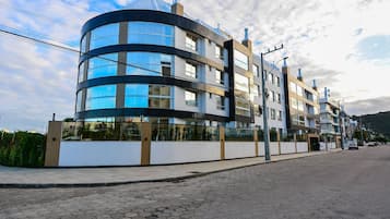 A modern multi-story building with a curved facade, large windows, and a flat roof.