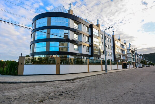 A modern multi-story building with a curved facade, large windows, and a flat roof.