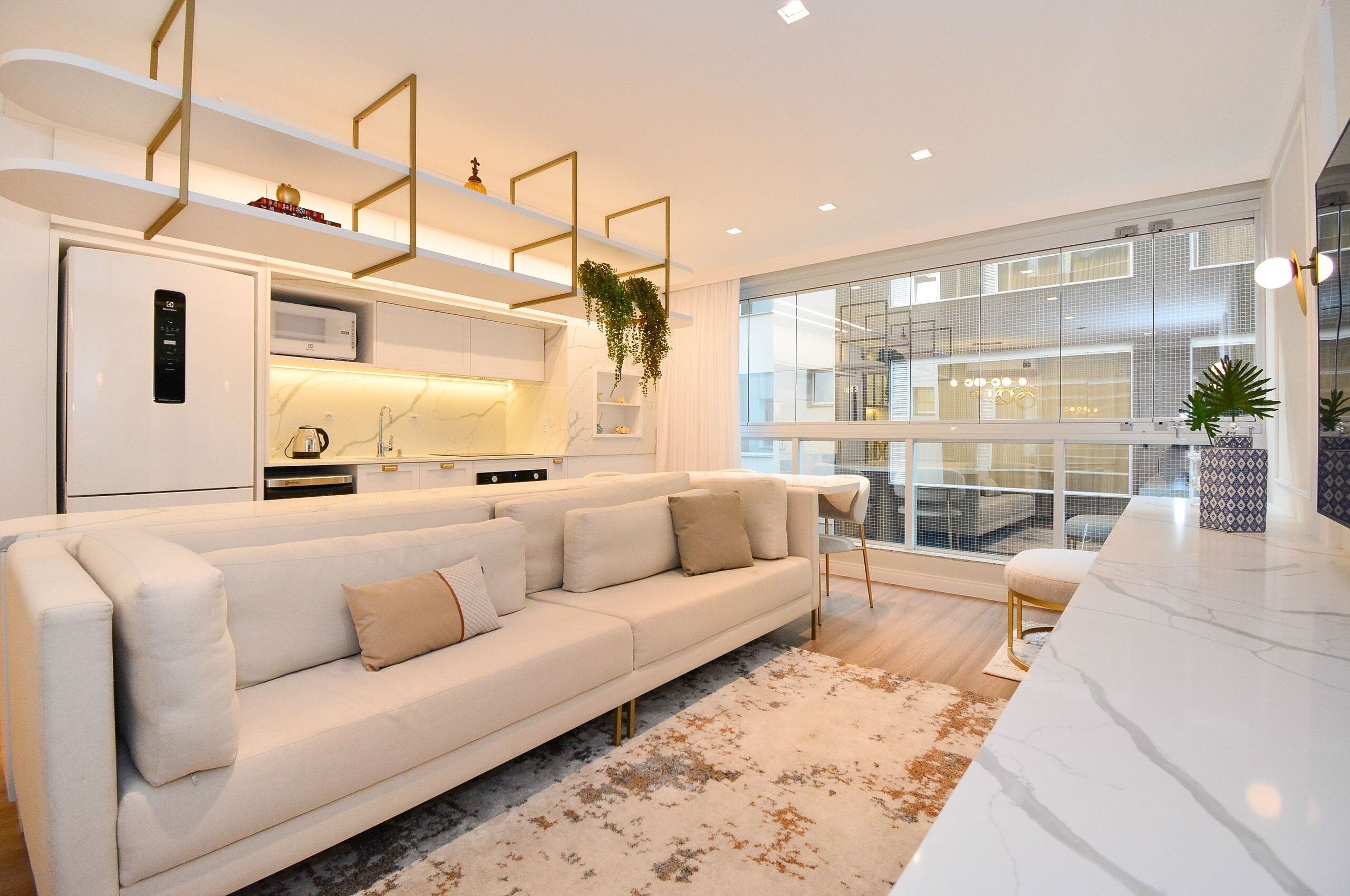 Uma sala de estar moderna com um sofá branco, uma bancada de mármore e uma janela grande com vista para a cidade.