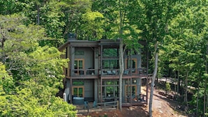 A multi-story cabin with a balcony on each floor, surrounded by dense forest. - Luxury Blackbird Cabin | Views, Hot Tub & Fire Pit (Blue Ridge)