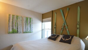 A bedroom with a large bed, two pillows with deer antlers, and a wall with two paintings of birch trees. - Excellent Location on Main Street, Breckenridge!  2 Bedroom/2 Bath (Breckenridge)