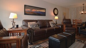 A living room with a brown leather sofa, a wooden coffee table, and a rug. There is a painting on the wall and a clock. - Excellent Location on Main Street, Breckenridge!  2 Bedroom/2 Bath (Breckenridge)