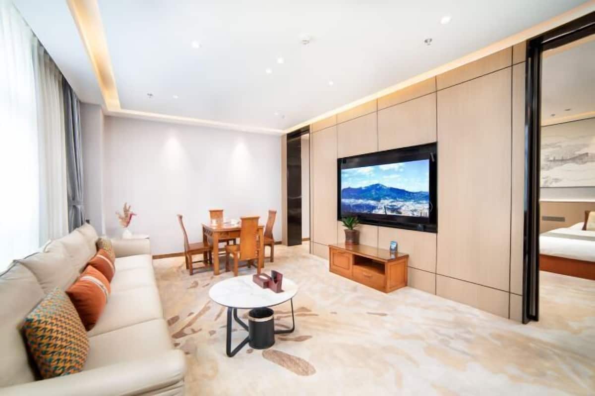 A modern living room with a sofa, coffee table, TV, and a dining area.