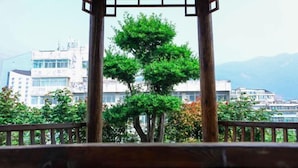 A wooden pergola structure with a view of buildings and mountains in the background. - Tai'an Shanhai Hotel (Tianwaicun) (Tai'an)