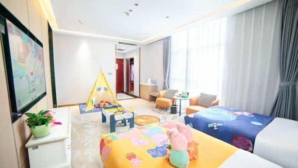 A hotel room with a bed, a desk, a chair, a small table, a potted plant, and a window with curtains. - Tai'an Shanhai Hotel (Tianwaicun) (Tai'an)