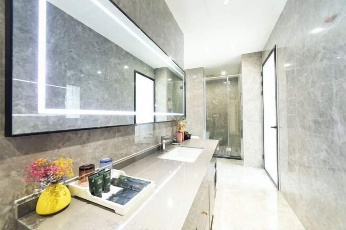 A modern bathroom with a large mirror, a vanity with a sink, and a shower area.