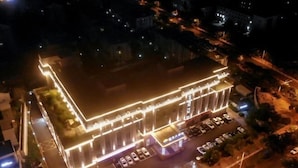 An aerial view of a hotel with a prominent illuminated facade, a parking area, and a street view. - Tai'an Shanhai Hotel (Tianwaicun) (Tai'an)