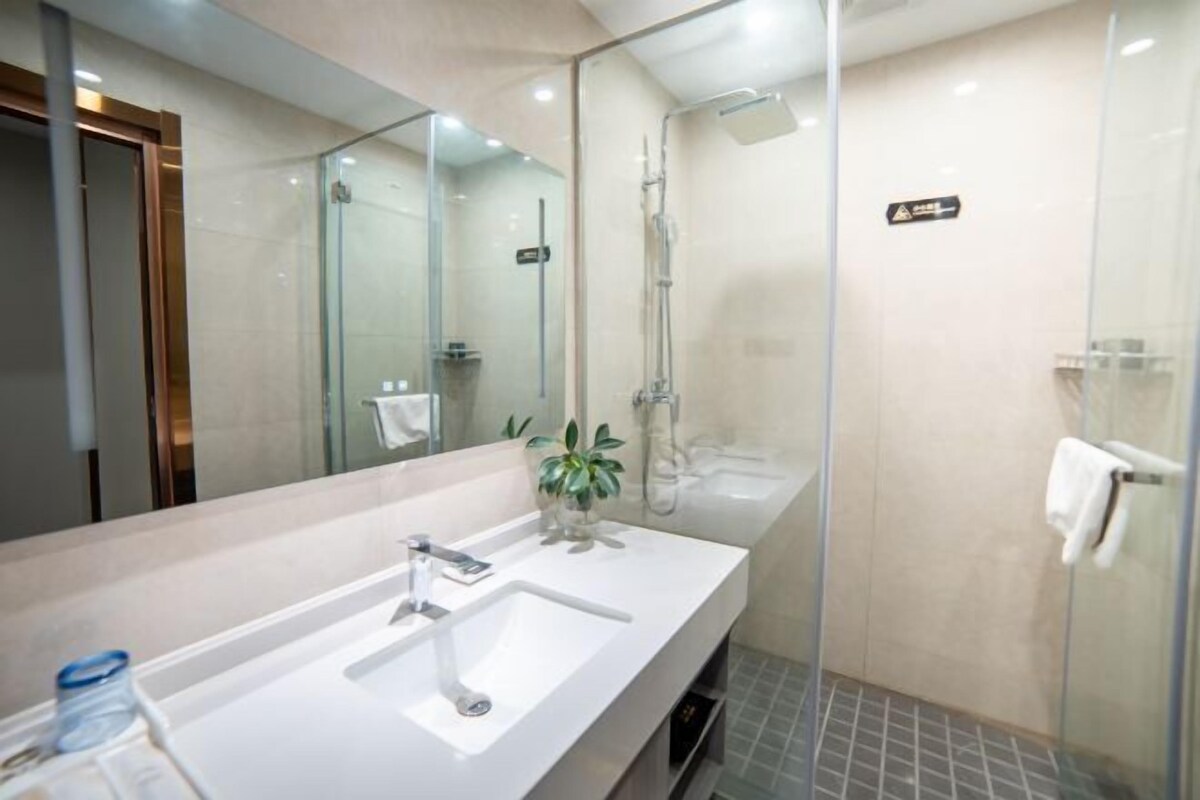 Une salle de bain moderne avec une douche à parois de verre, un grand miroir et un lavabo blanc.
