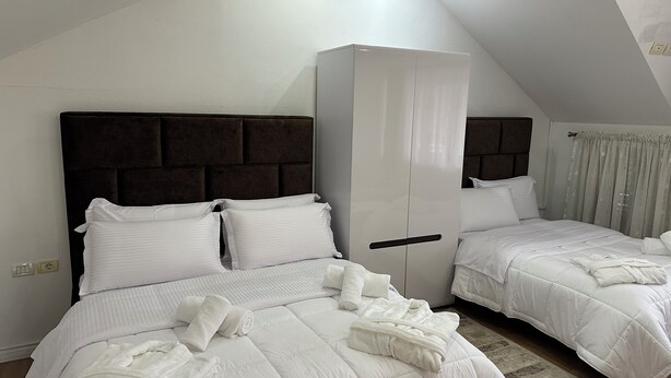 Une chambre d’hôtel avec deux lits, une armoire et un luminaire au plafond.